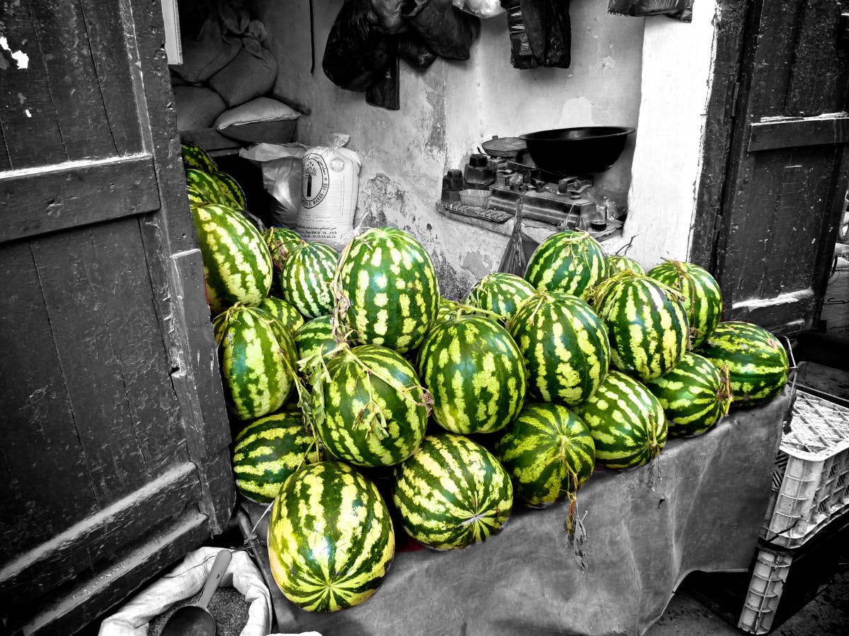 a table full of bright green watermelons at a market stall